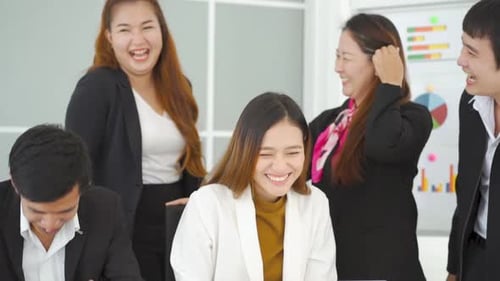 Smiling Colleagues Gathered Around Laptop in Office