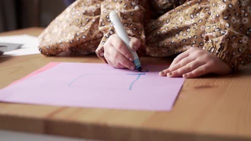 Child Drawing on Pink Paper with Blue Marker