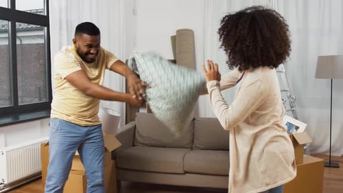 Happy Couple Having Pillow Fight at New Home