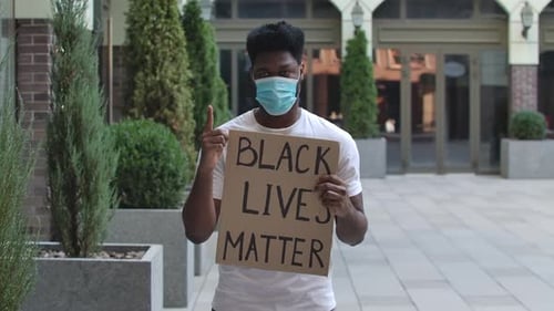 Young Adult Holding Protest Sign in Urban Setting