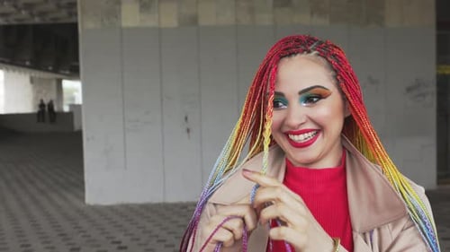 Chica de moda con una chaqueta endereza sus trenzas africanas de colores