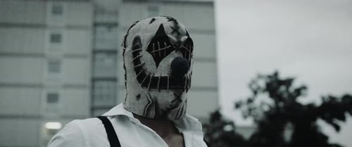 Figure in Clown Mask with Apartment Building Backdrop
