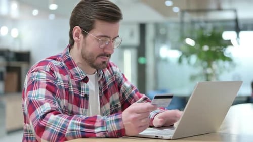 Mann macht Online-Zahlung auf Laptop im Café
