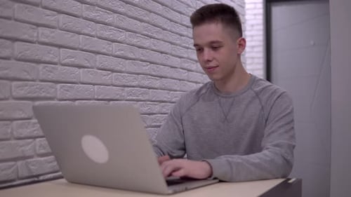 Young Adult Typing on Laptop at Desk Indoors