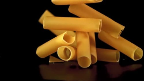 Tube Pasta Falling onto Black Reflective Surface