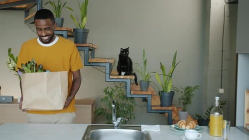 Young Man Unpacks Groceries in Bright Kitchen