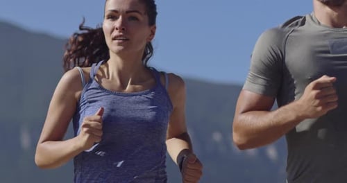 Tracking Slow Motion Shot of Sportive Couple Jogging Outdoors in the Morning Trail Running