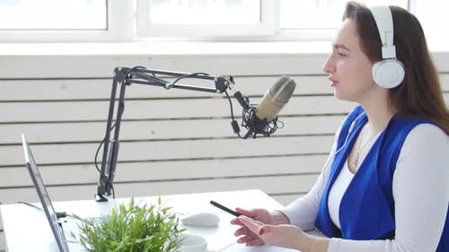 Woman Speaking Into Microphone Broadcasting From Home Office