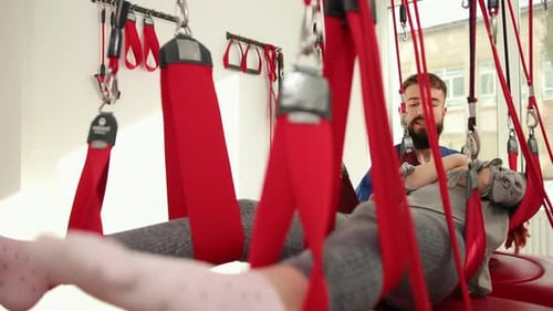 Medical Specialist Adjusting Woman in Treatment Straps
