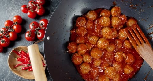 Frying Pan with Meatballs and Wooden Shovel Rotates Slowly.