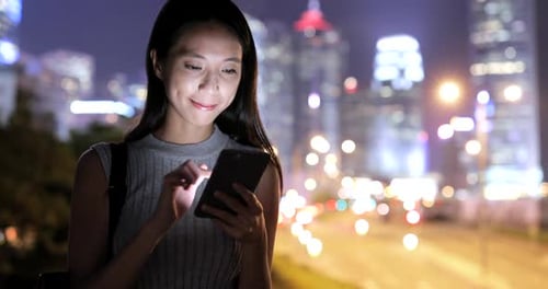 Woman Using Phone at Night in the City