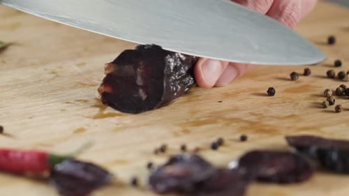 Dried Sausage Being Sliced on Cutting Board