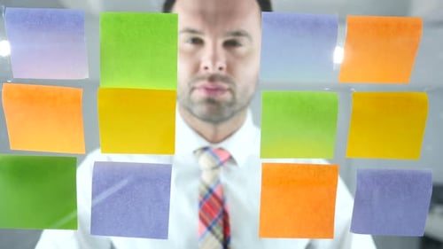 Man Working On Sticky Notes Attached on Glass in Office