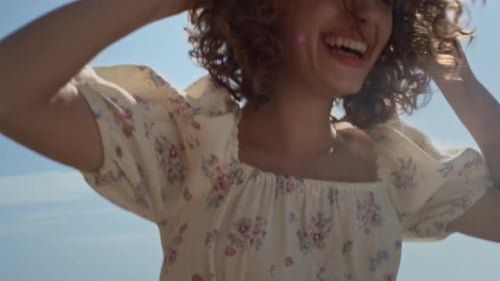 Smiling Woman Adjusts Straw Hat in Bright Sunlight