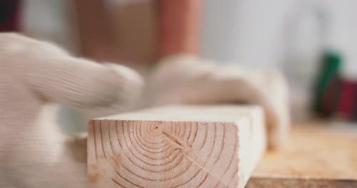 Professional Carpenter Cleans and Checks with His Hand the Edges of the Beam After Cutting with a