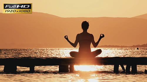 Woman Meditating on Dock at Sunrise