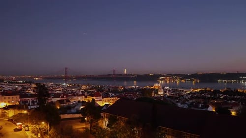 Aerial view of Alfama in Lisbon with some cars going home on the bridge 25 de Abril (Ponte 25 de Abr