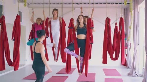 Women Exercising Aerial Yoga with Red Silks