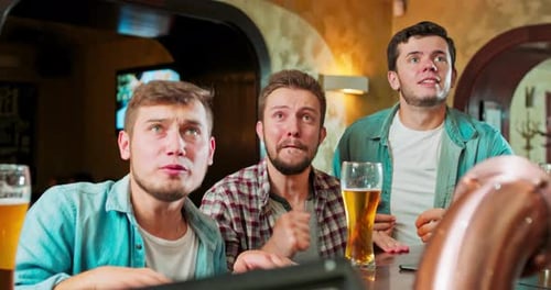 Guys Fans of Football Watching Match Together in Evening in Pub and Worrying for Their