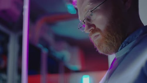 Data Center Technician Working on Tablet in Server Room