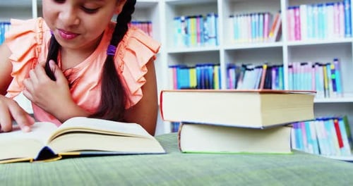 Schoolgirl reading book in library at school