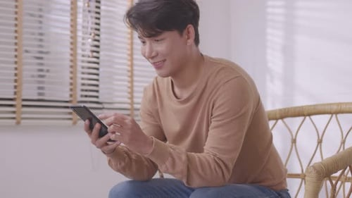 Young Adult Using Phone Indoors by Window