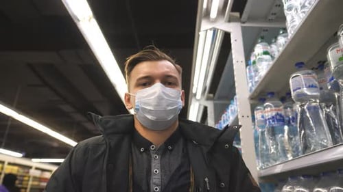 Portrait of Young Man with Medical Face Mask Walking at Supermarket. Guy Going at Shop with