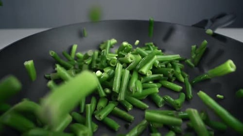 Französische Bohnen fallen in Zeitlupe in die Pfanne, frisches Gemüse fällt in 240 Fps, Kochen