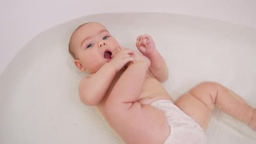 Happy Infant Bathing in White Tub