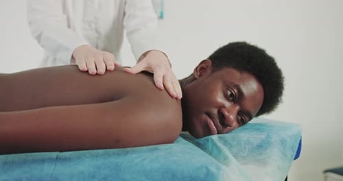 Physiotherapist Conducts Massage Therapy To African Young Man To Restore Muscle