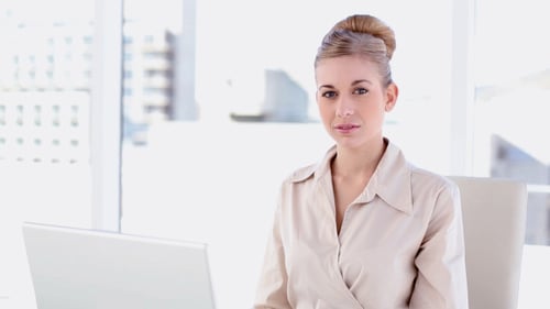 Smiling Woman Working on Laptop in Bright Office