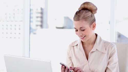 Young Woman Uses Smartphone at Office Desk