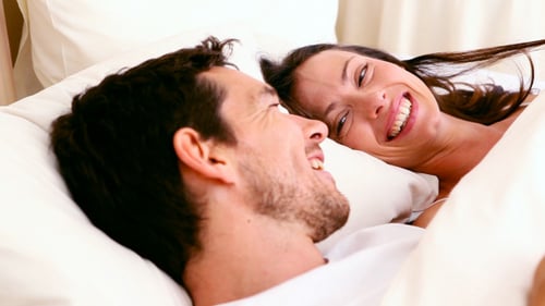 Glückliches Paar liegt im Bett und plaudert
