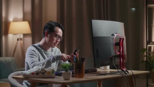 Man Uses Smartphone at Desk in Home Interior