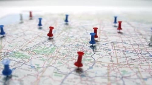 Camera pan revealing red white and blue pins placed marking cities on a US map.