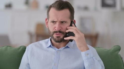 Man Frustrated on Phone Call Indoors