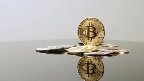 Gold Bitcoin Coins Pile on Reflective Surface