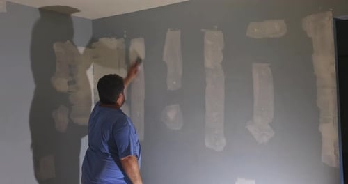 Construction Worker Repairing Wall in Home
