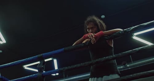 Focused Man Leaning on Boxing Ring Ropes