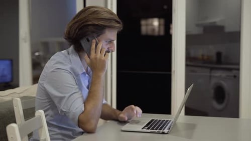 Young Adult Working at Home with Laptop and Phone