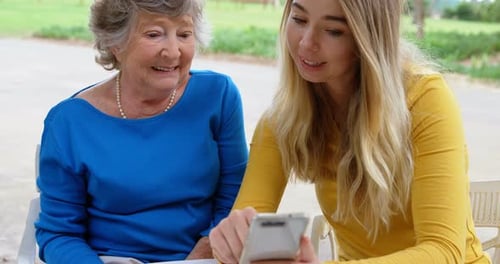 Woman Shows Senior Woman Something on Smartphone