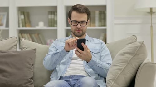 Man Using Smartphone on Couch at Home