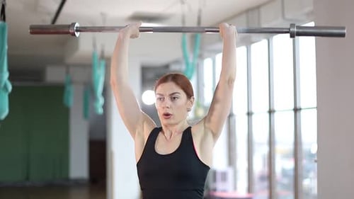 A woman lifts a barbell in the gym, a fitness woman does strength exercises