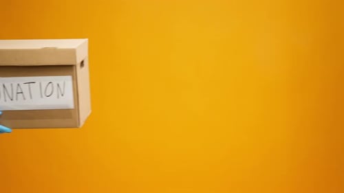 Donation Box Held by Person Wearing Blue Gloves