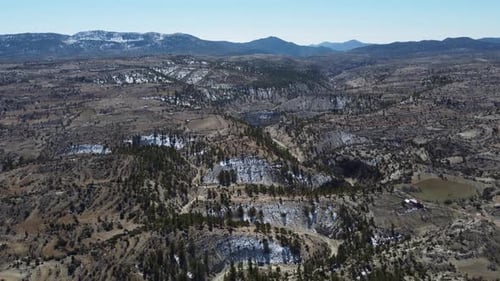 Drone View Over Meandering Valley Against Snowy Mountains