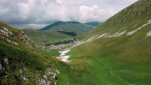 Flying Over Beautiful Mountain Valley Covered with Stones and Snow with Grass Under Wonderful