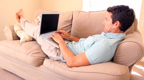 Man Relaxing on Couch Typing on Laptop