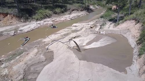 Long Thin Pipe Extracts Wet Sand From Narrow Muddy River