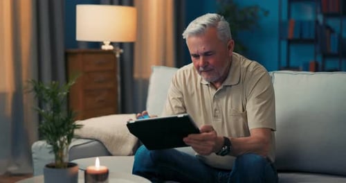Senior Adult Relaxing at Home with Tablet