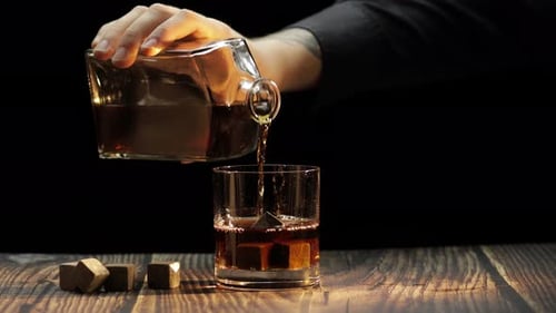 Verser du whisky et du cognac dans un verre. Fond noir. Boisson alcoolisée